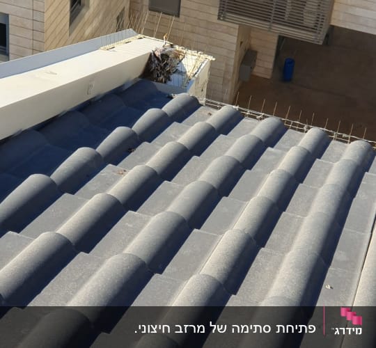 גג רעפים עם קורות בטון וברזלים בולטים